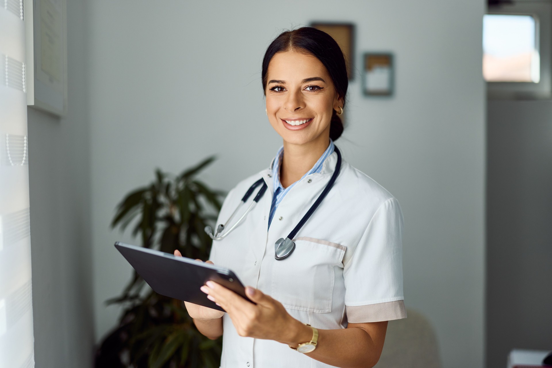 Smiling Female Doctor Holding a Tablet in a Professional Medical Office