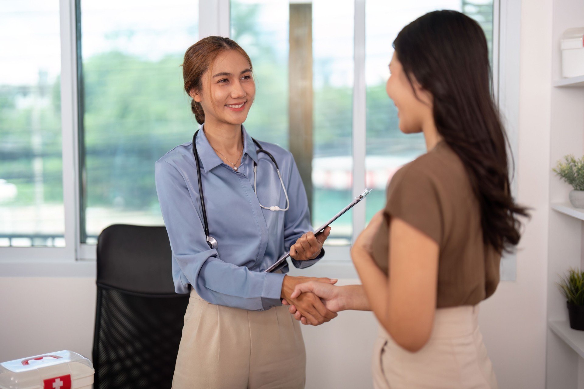 Positive Healthcare Encounter. Nurse and patient sharing a handshake in a consultation.