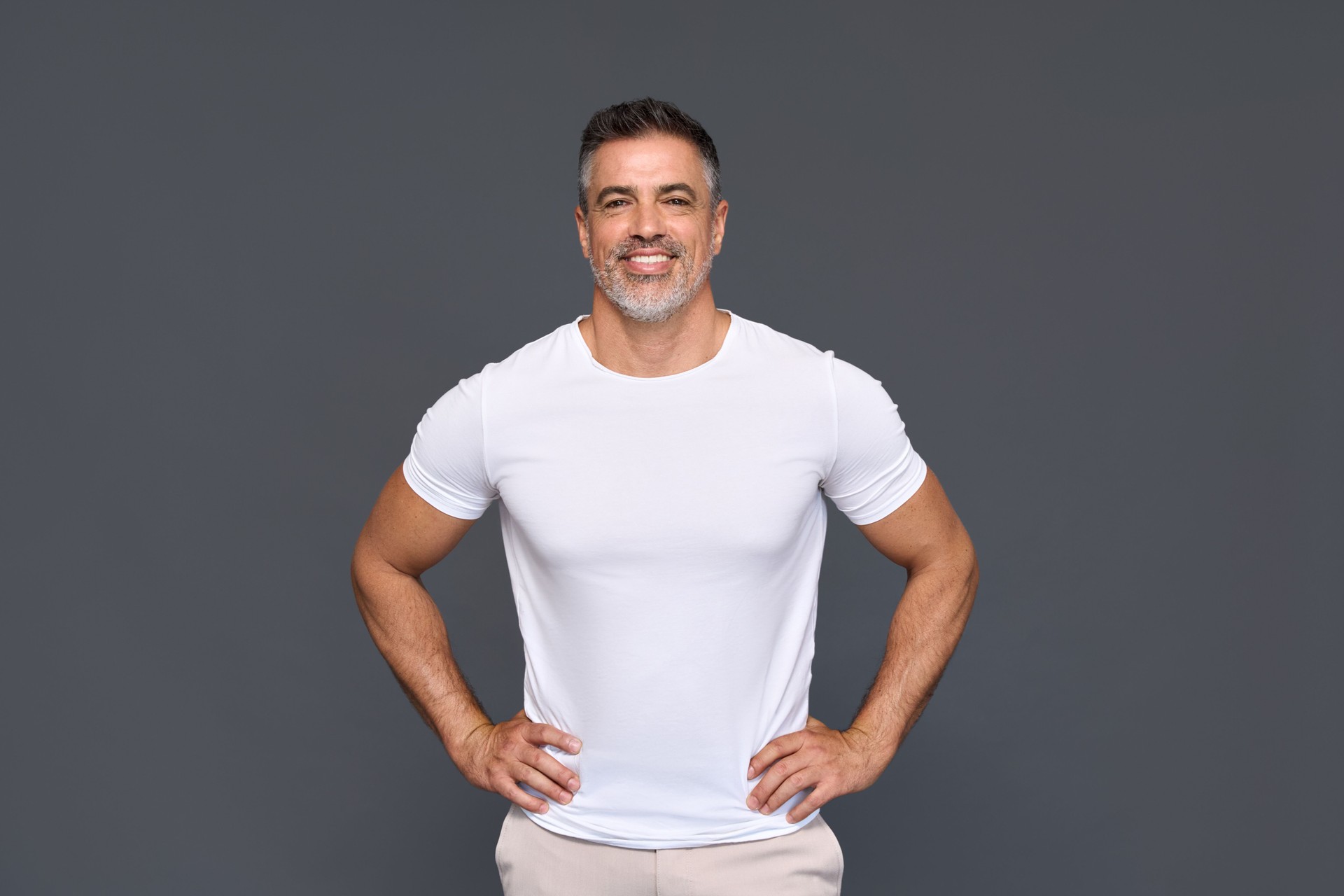 Happy fit sporty mature older man wearing white t-shirt isolated on background.