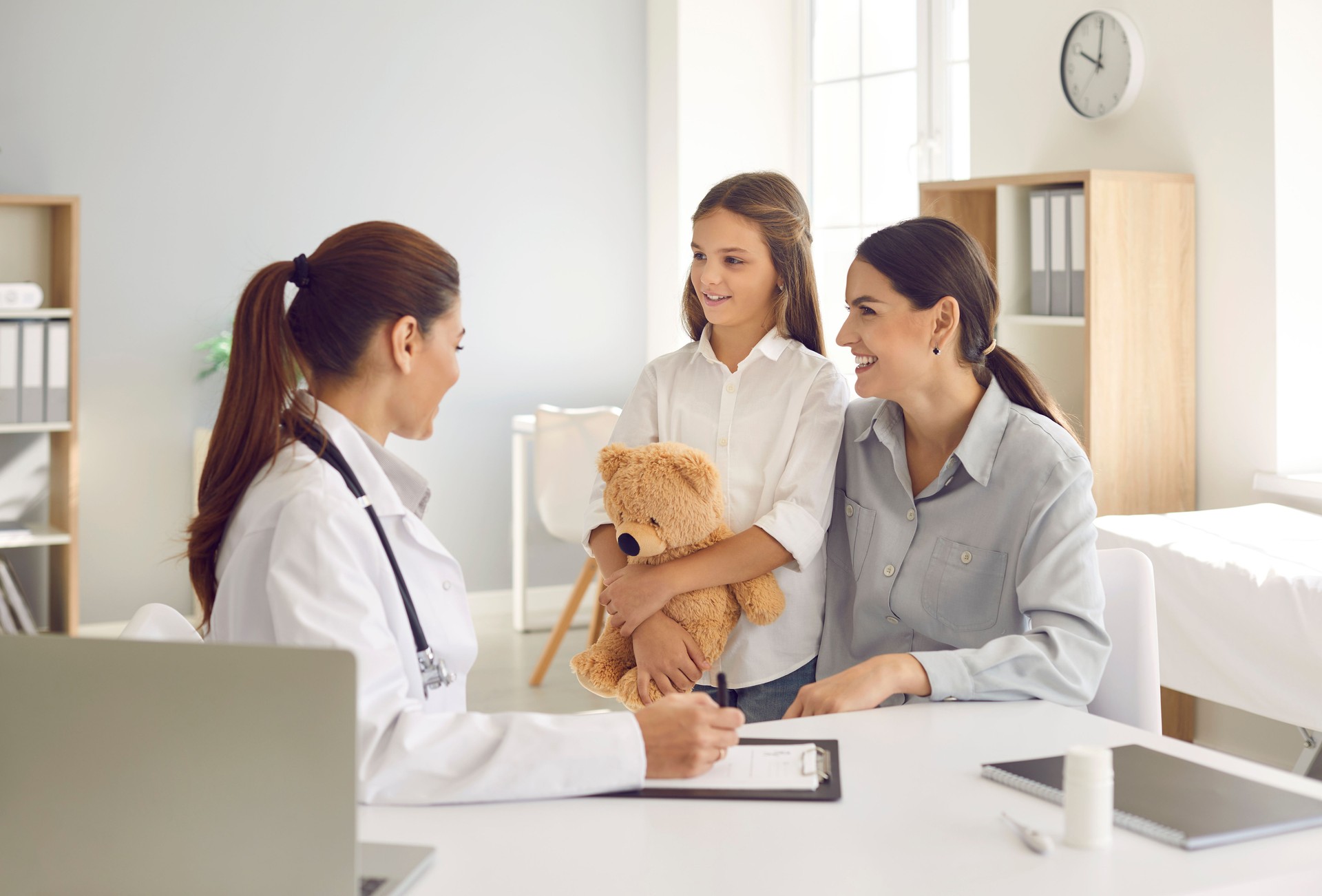 Happy mother and her little daughter talking to their family doctor at the hospital