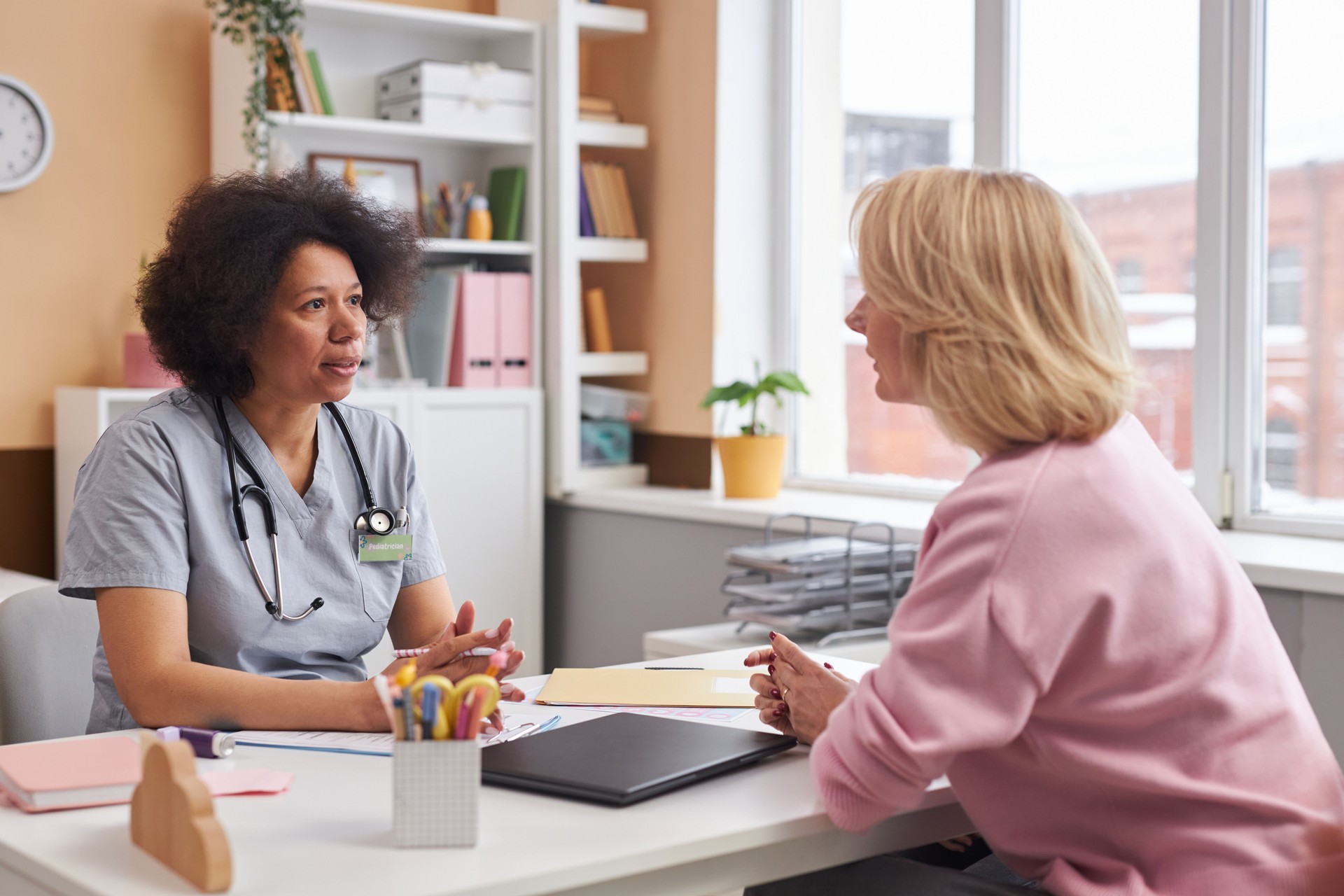 Black Woman as Pediatrician Talking to Mother in Clinic
